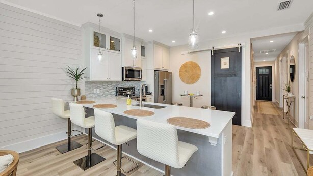 Una cocina moderna con una isla central, taburetes de bar e iluminaci ón colgante.
