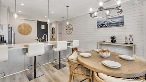 Una cocina moderna con una isla central, taburetes de bar y un comedor con una mesa redonda y sillas.