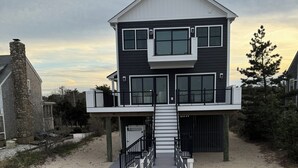 Une maison à deux étages avec une terrasse en bois menant à l’entrée.