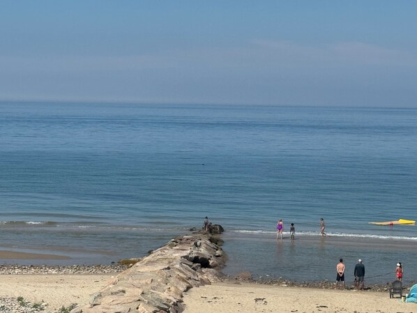 Una playa con costa rocosa y mar tranquilo.