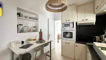 Een koelkast, een microgolfoven, kookgerei, borden en bestek