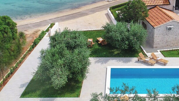 A coastal villa with a swimming pool, a dock, and boats in the background. - Holiday Home Lovište (Orebic)