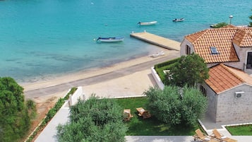 Una villa costera con piscina, muelle y barcos al fondo.