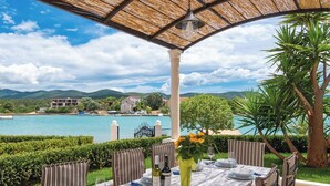 An outdoor dining area with a table set for four, overlooking a body of water and a mountainous landscape. - Holiday Home Lovište (Orebic)