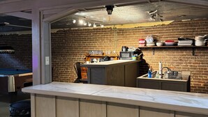 Eine Bar mit Backsteinwand, Holzboden und verschiedenen Küchengeräten.