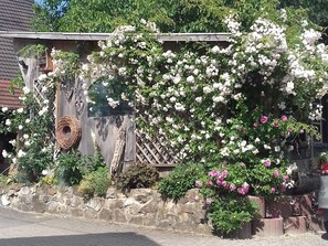 Un edificio rústico con pared de piedra, cerca de madera y diversos plantas en flor.