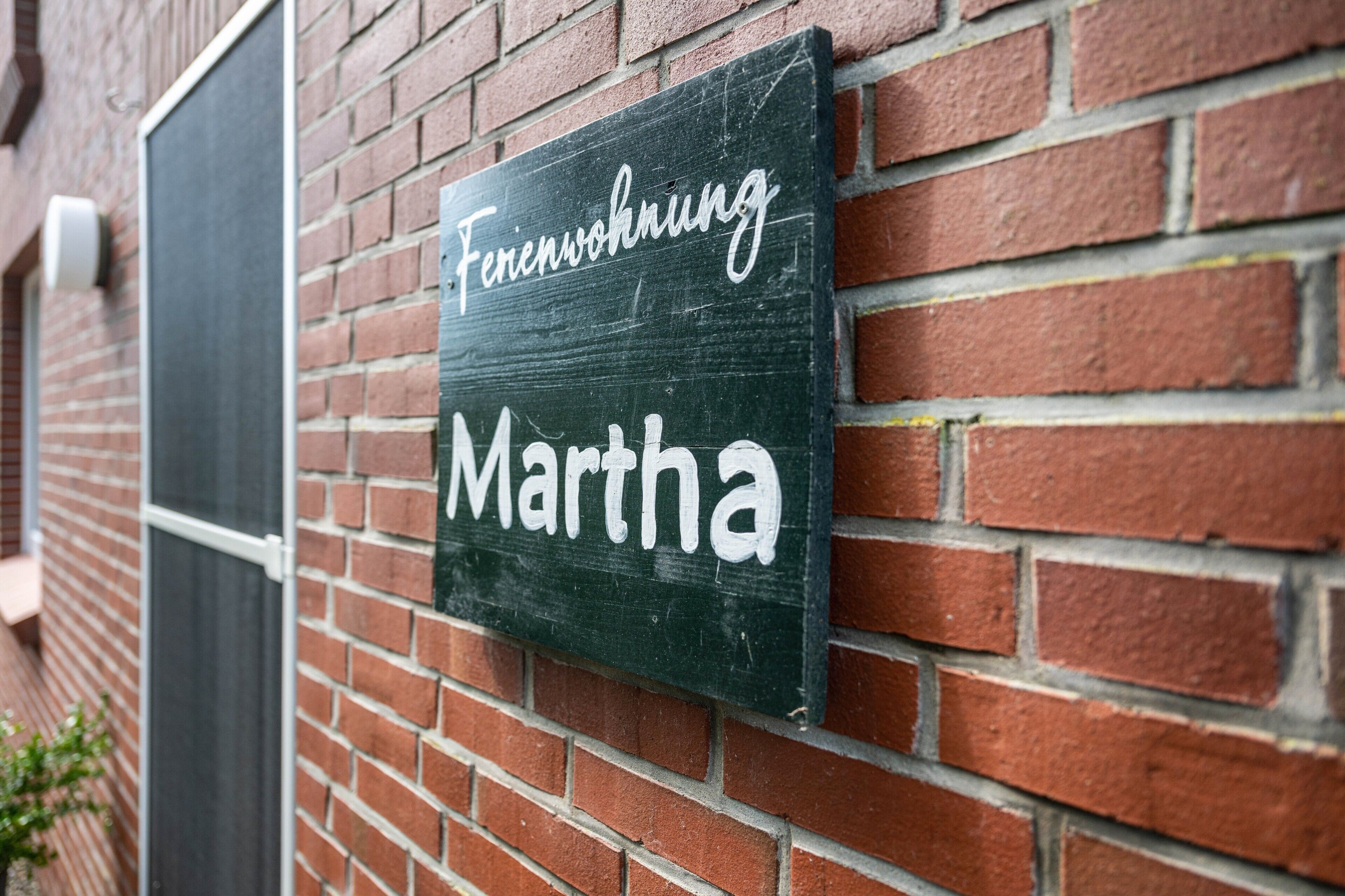 Un letrero con la frase 'Fahrenwohnung Martha' en una pared de ladrillo.