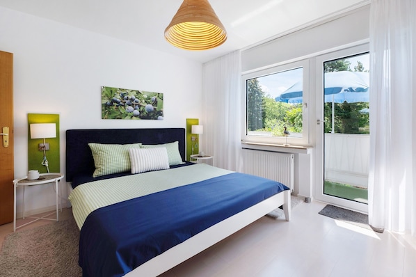 Ein Schlafzimmer mit Bett, Fenster, Tür und einer Wandlampe.