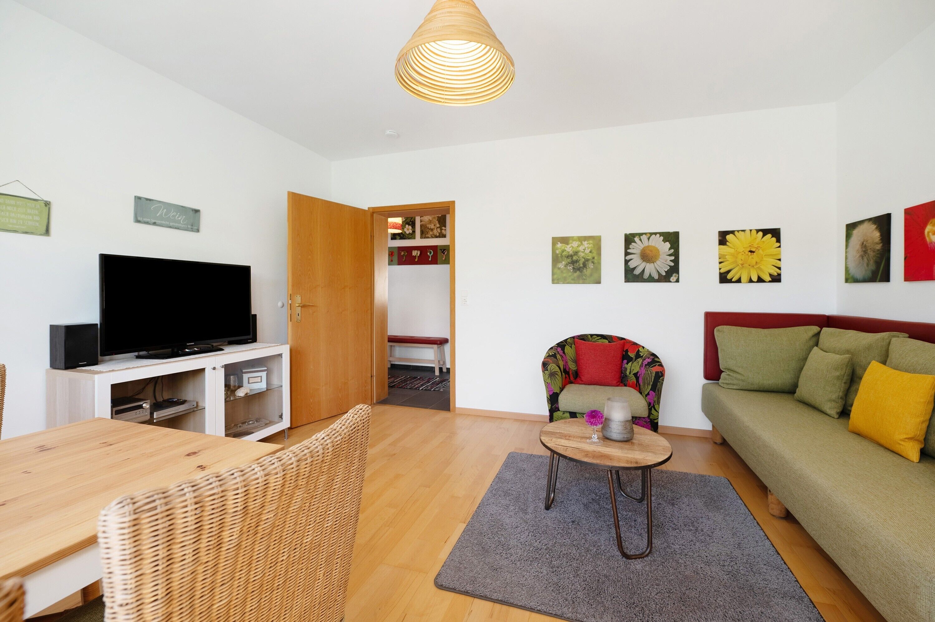 Een woonkamer met een televisie, een bank, een eettafel en een stoel.