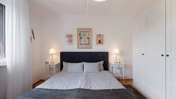 Una camera da letto con un letto, due comodini, un armadio e tre quadri appesi al muro.
