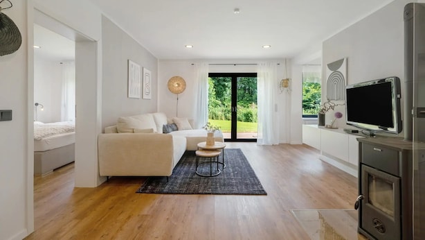 A modern living room with a sofa, a small round table, and a television.