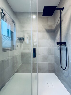 Eine moderne Dusche mit Glastrennwand, Handtuchhalter und einem sichtbaren Waschbecken.
