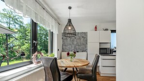 A modern kitchen with white cabinets, a round wooden table, and two black chairs.