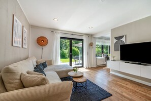 Un salon moderne comprenant un canapé, une table basse, un téléviseur et une porte-fenêtre coulissante donnant sur un espace extérieur.