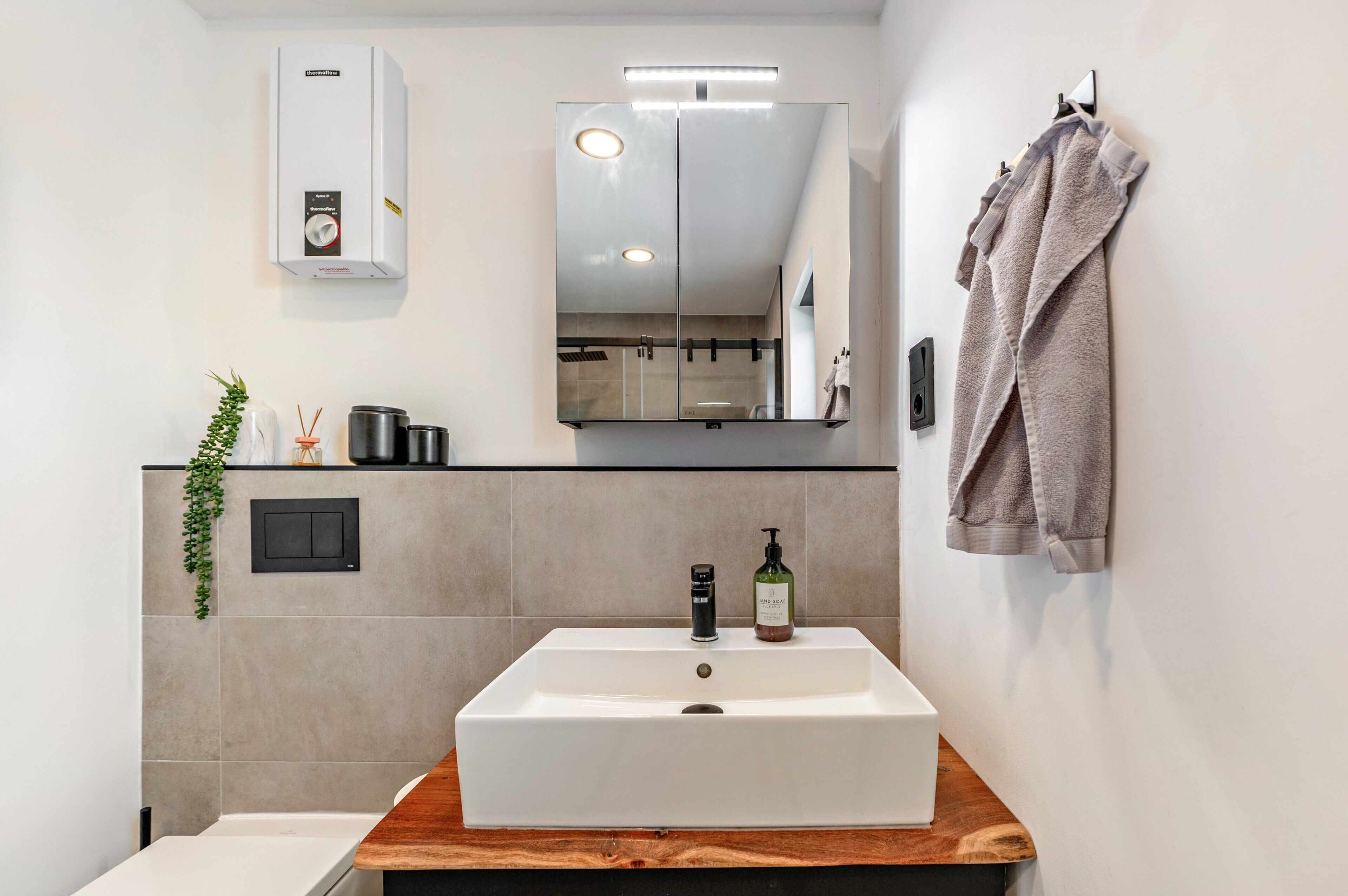 Un bagno moderno con un lavandino rettangolare, uno specchio, un porta asciugamani e un termosifone a parete.