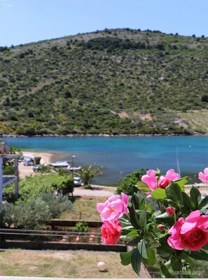 A view of a coastal area with a beach and a hill in the background. - Apartments Juras (Rogoznica)