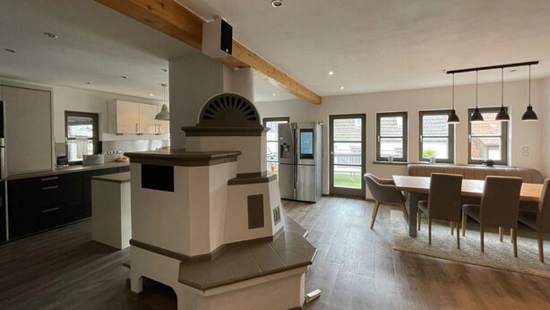 Een moderne keuken met een ingebouwde oven, een eethoek met een bank en een groot raam.