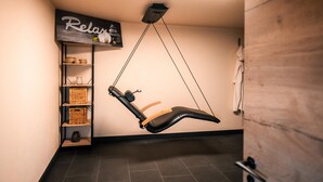 Een kamer met een massagestoel, planken met manden, en een bordje waarop staat 'Ontspan'.