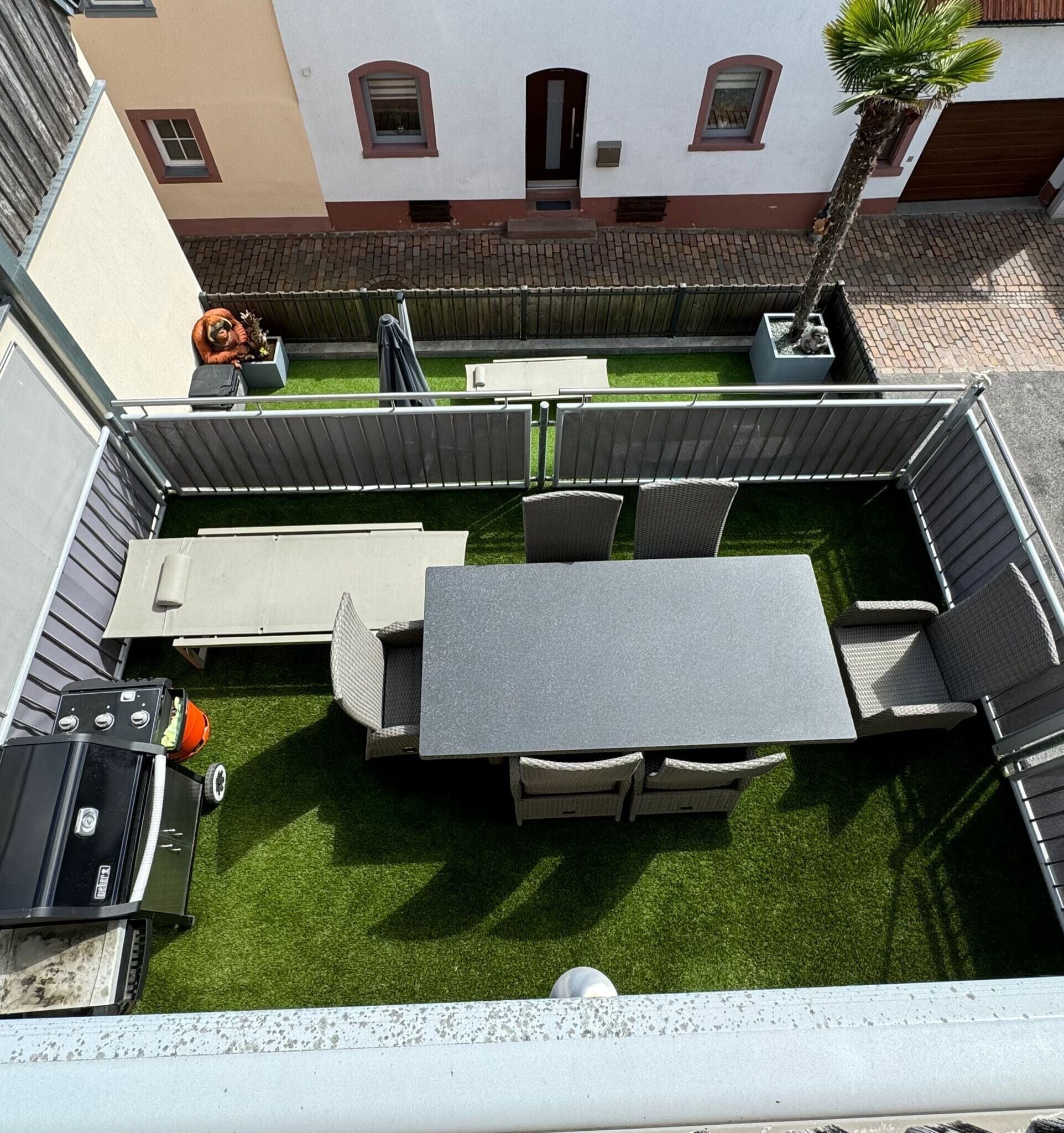 Eine Dachterrasse mit Essbereich, Grill und einer kleinen Statue.