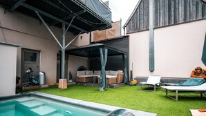Een zwembadgedeelte met een jacuzzi, buitenzitplaatsen en een overdekt terras.
