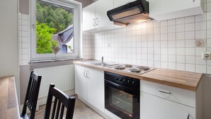 Eine Küche mit weißen Schränken, einer Holz Arbeitsplatte, einem eingebauten Backofen und einem Fenster mit Blick auf Bäume.