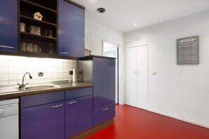 A kitchen with a sink, cabinets, and a refrigerator.