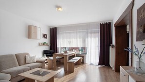 Un salon moderne comprenant un canapé, une table basse et un coin repas avec des bancs.
