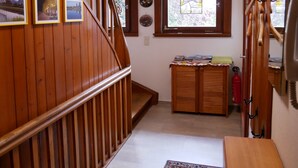 Un escalier en bois avec une rampe, une petite table recouverte de papiers, un extincteur et une fenêtre ornée de vitraux.