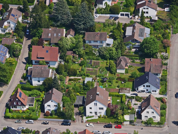 An aerial view of a residential area with houses, roads, and greenery.