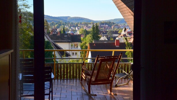 Un balcon donnant sur la ville, un fauteuil à bascule et une table.