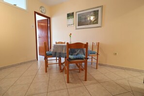 A dining area with a wooden table and chairs, a clock on the wall, and a framed picture of Ireland. - Seaside Apartments Markota (Blato)