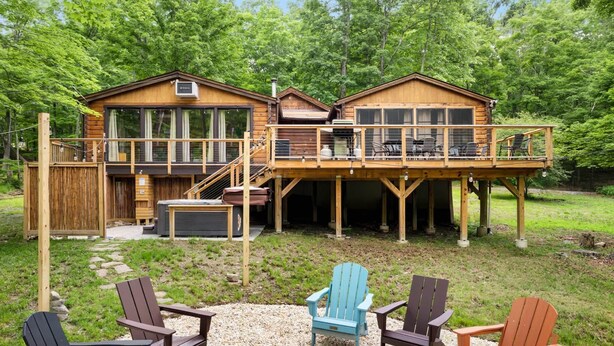 Eine Hütte mit einer Terrasse, Sitzgelegenheiten im Freien und Wald im Hintergrund.