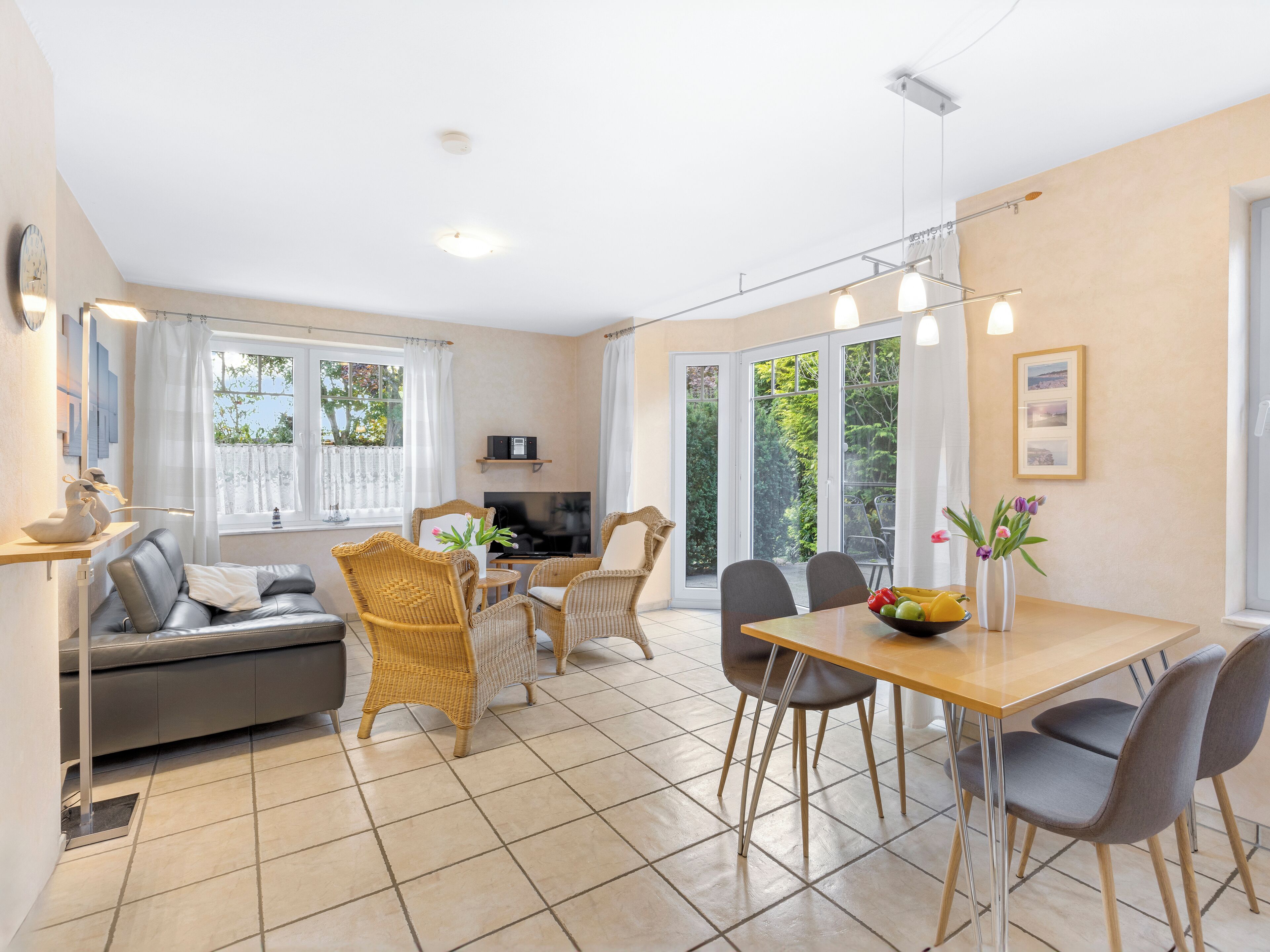 A modern living room with a sofa, dining table, chairs, and a TV.