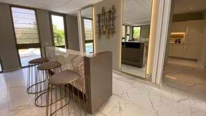Una cocina moderna con encimera de mármol, una barra con taburetes y un espejo grande que refleja la cocina.
