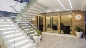 Un interior moderno con una escalera de cristal, una zona de recepción y un espacio para comer.