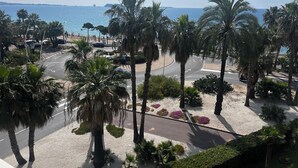 Een kustweg met palmbomen en een strand op de achtergrond.