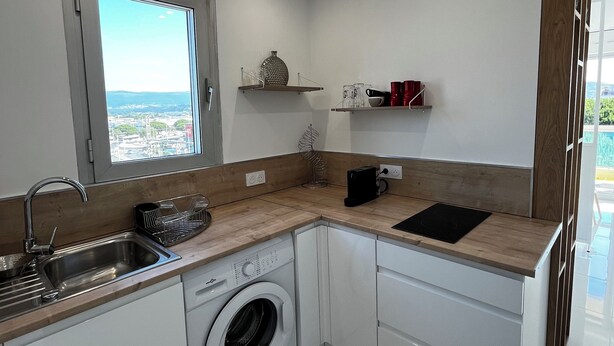 Een praktische keuken met een wasmachine, een gootsteen en een raam met uitzicht over de stad.