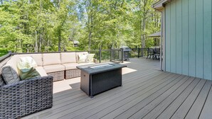 Une terrasse avec un canapé, des chaises et une table, entourée d’arbres.