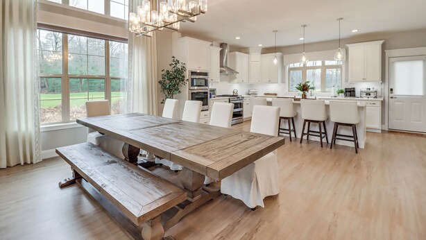 Une cuisine spacieuse avec une grande table en bois, des armoires blanches et des luminaires suspendus.