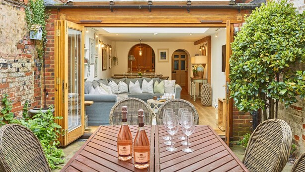 Une terrasse accueillante avec une table en bois, deux bouteilles de vin rosé et quatre verres à vin.