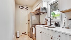 Cocina compacta con electrodomésticos de acero inoxidable, una ventana con vistas y un letrero que indica que es la cocina.