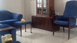 A living room with a blue sofa set, a wooden cabinet, and a chandelier. - Hanaia House (Zanzibar Town)