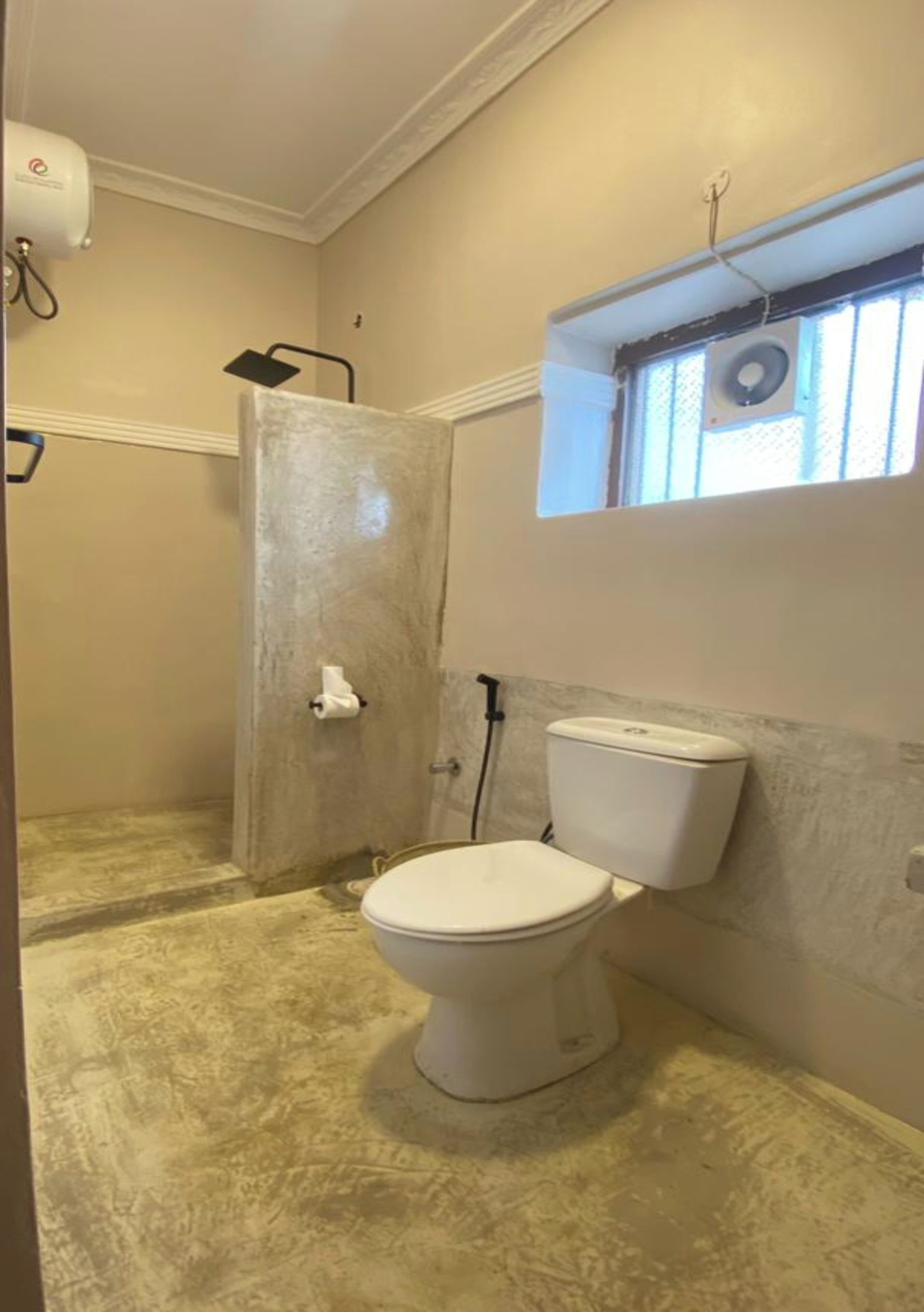 A bathroom with a toilet, a shower, and a window with a small skylight.