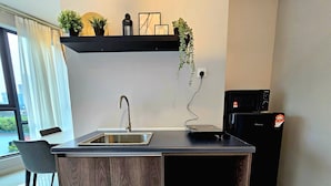 Una cocina moderna con un lavamanos empotrado, un refrigerador compacto y un armario de madera.