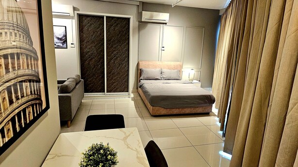 Un dormitorio moderno con cama, escritorio con planta, ventana grande y aire acondicionado de pared.