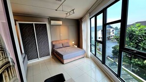 Un dormitorio moderno con cama, mesita de noche, ventana con vista a la calle y puerta que da a otra habitación.