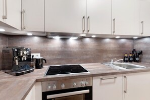Une cuisine équipée d’une cuisinière, d’un four et d’un évier, ainsi que d’appareils électroménagers et de meubles de rangement modernes.