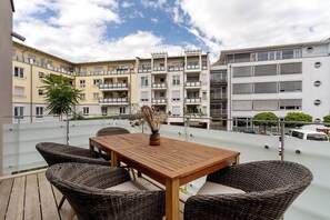 A rooftop terrace with wicker furniture, a wooden table, and a vase of dried flowers. - Holiday Apartment "Km Style 5" with Balcony & Wi-Fi (Freiburg im Breisgau)
