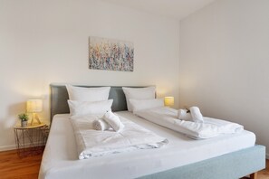 A double bed with white linens, two bedside lamps, and a wall-mounted abstract painting. - Holiday Apartment "Km Style 5" with Balcony & Wi-Fi (Freiburg im Breisgau)