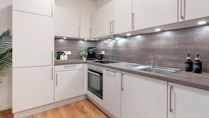 A modern kitchen with white cabinets, a stainless steel sink, a built-in oven, and a coffee machine. - Holiday Apartment "Km Style 5" with Balcony & Wi-Fi (Freiburg im Breisgau)